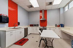 Kitchen featuring light countertops, white cabinets, stainless steel appliances, and a paneled ceiling