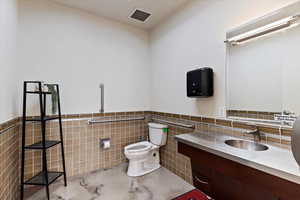 Bathroom 2 featuring vanity, tile walls, and wainscoting