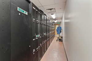 Hall with a paneled ceiling, finished concrete flooring, and a package area