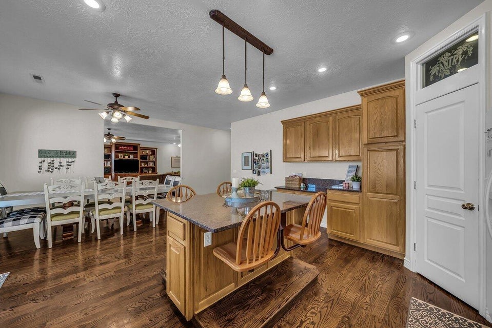 Kitchen featuring dark wood-style floors, wood finish cabinetry, dark stone counters, a textured ceiling, and decorative light fixtures