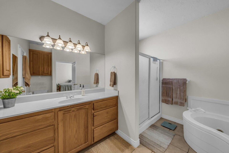 Full bath featuring vanity, a shower stall, light tile patterned floors, and a garden tub