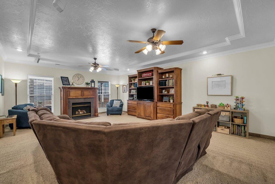 Living room featuring crown molding, light carpet, a fireplace, recessed lighting, and a ceiling fan