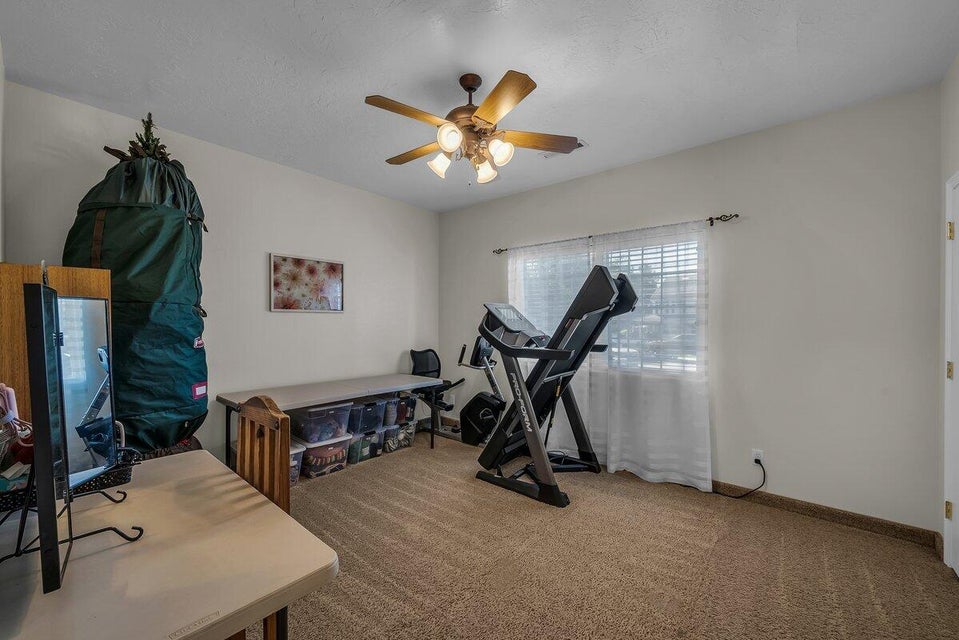 Workout room with light colored carpet, ceiling fan, and a textured ceiling