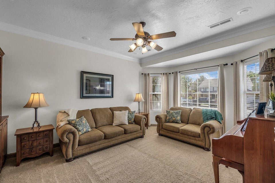 Carpeted living room with crown molding, a textured ceiling, and a ceiling fan