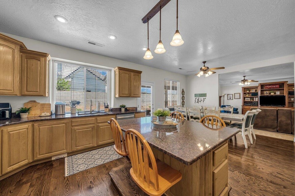 Kitchen with dark wood-style floors, dark stone counters, a textured ceiling, a kitchen bar, and open floor plan