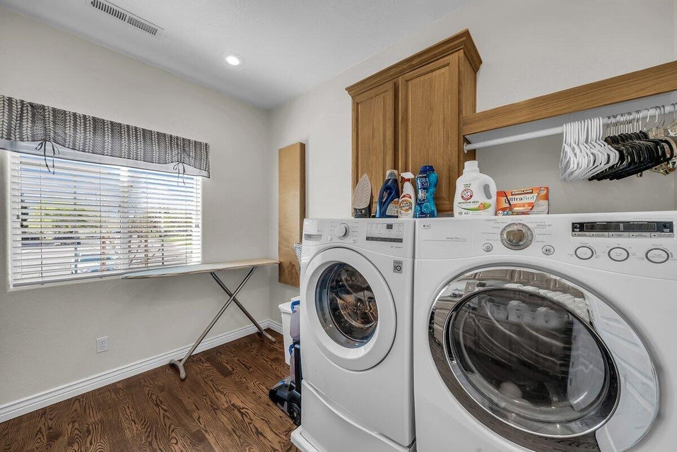 Laundry room with washer and clothes dryer, dark wood finished floors, and cabinet space