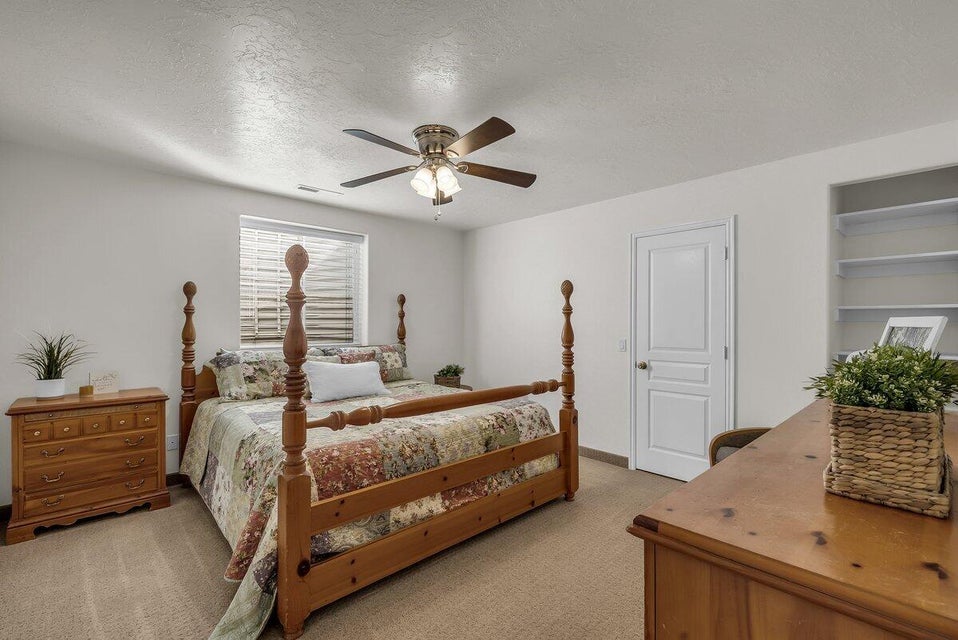 Bedroom with a textured ceiling, light colored carpet, and a ceiling fan