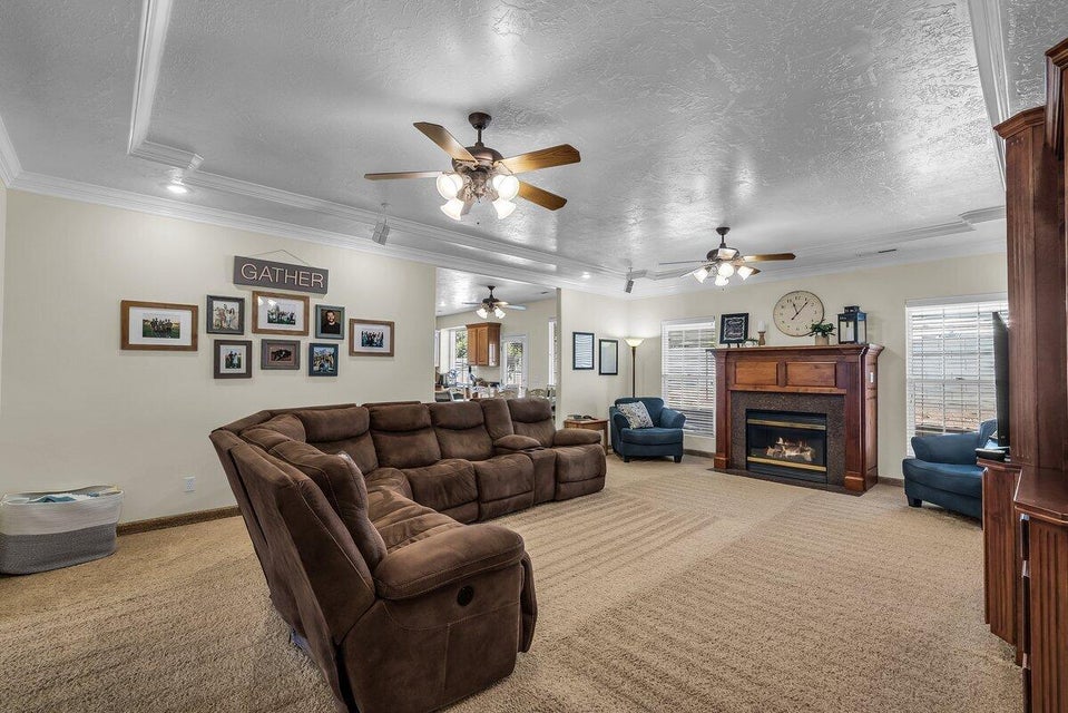 Carpeted living room with a textured ceiling, crown molding, a fireplace with flush hearth, and healthy amount of natural light