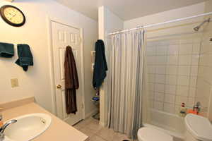 Bathroom featuring vanity, shower / bath combination with curtain, and light tile patterned flooring