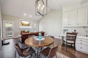 Dining room with lofted ceiling, a chandelier, dark wood-style flooring, and a fireplace