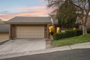 Ranch-style home featuring a shingled roof, concrete driveway, a garage, and brick siding