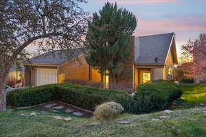 View of front of house with brick siding, a shingled roof, a front yard, and a chimney