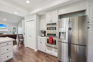 Kitchen featuring stainless steel appliances, light countertops, vaulted ceiling, dark wood-type flooring, and white cabinetry