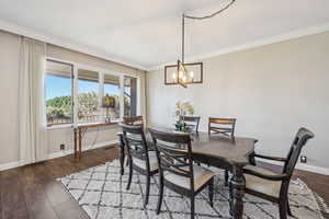 Dining area featuring dark wood-style floors, ornamental molding, and hanging lights
