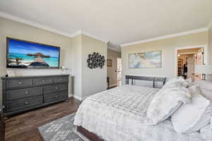 Bedroom with crown molding and dark wood-type flooring