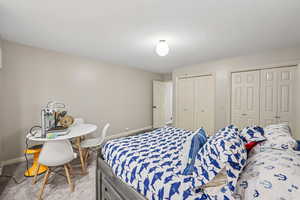 Carpeted bedroom featuring two closets and baseboards
