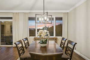 Dining area with hardwood / wood-style flooring, hanging lights, and ornamental molding
