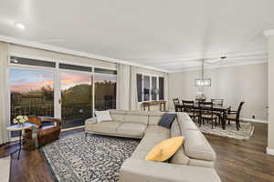 Living room featuring dark wood-style flooring and crown molding