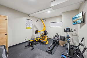 Workout room featuring dark colored carpet and baseboards