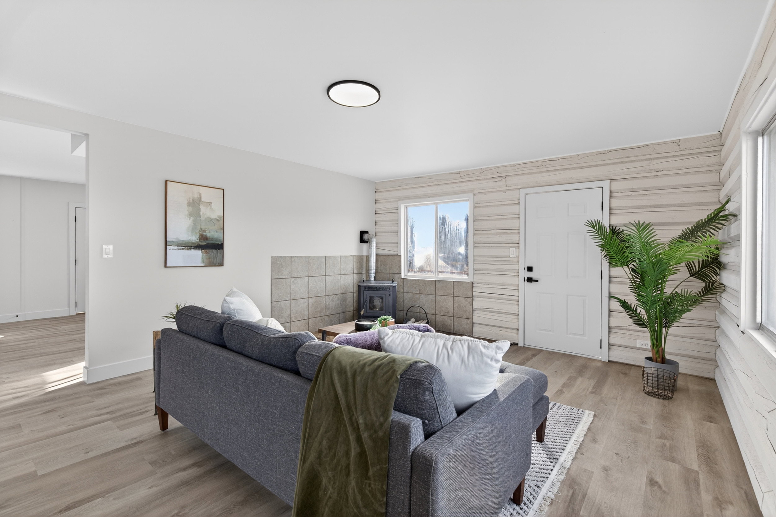 Living area with light wood-style floors, an accent wall, and a wood stove