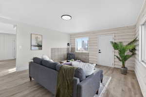 Living area with light wood-style floors, an accent wall, and a wood stove