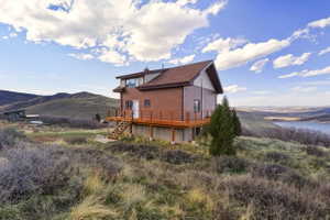 Rear view of property featuring a deck with water view and a chimney
