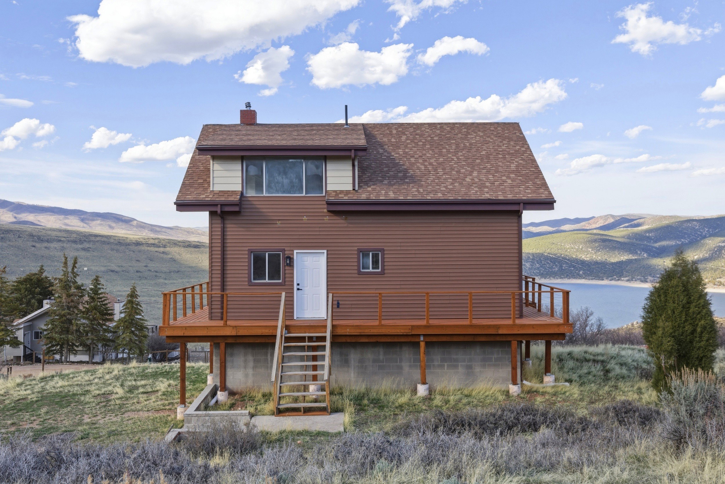Back of property with a deck with mountain view, a shingled roof, and a chimney