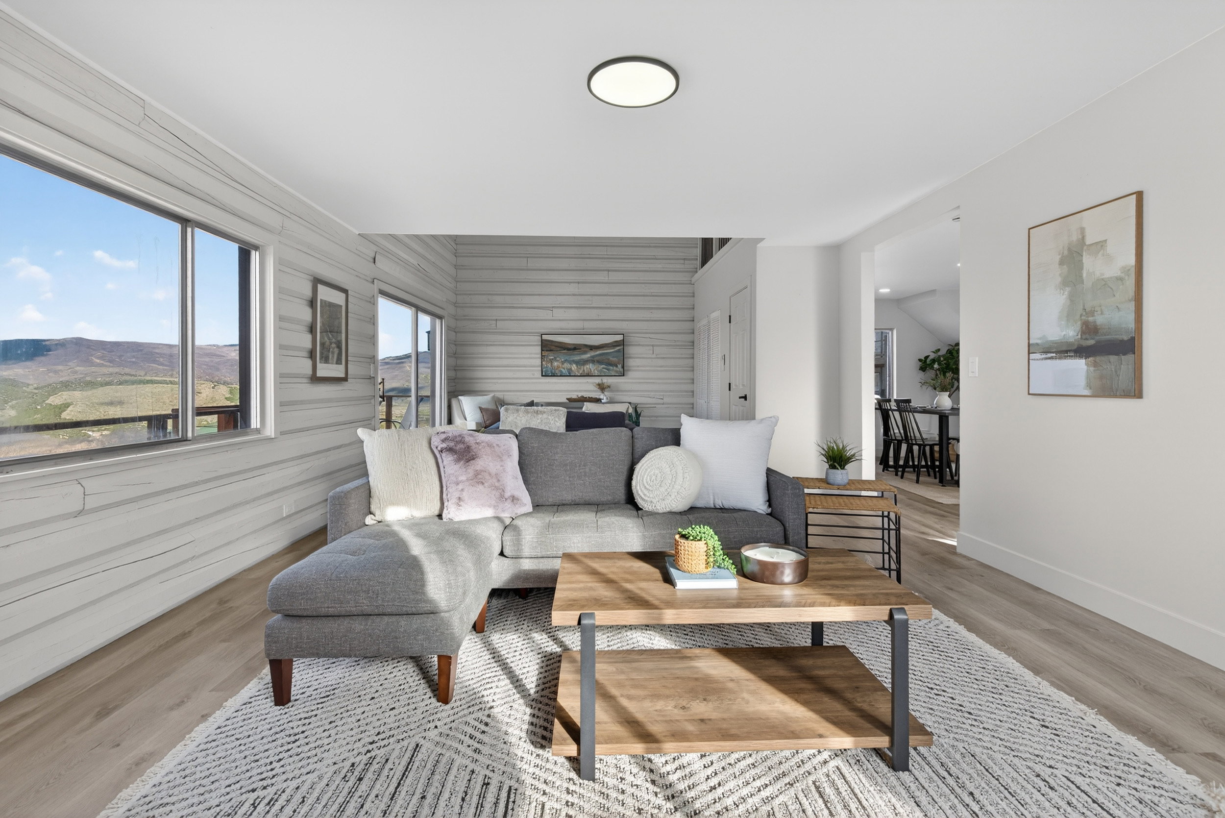 Living area with light wood-style floors, wood walls, an accent wall, and a mountain view