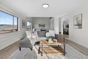 Living area with light wood-style floors, wood walls, an accent wall, and a mountain view