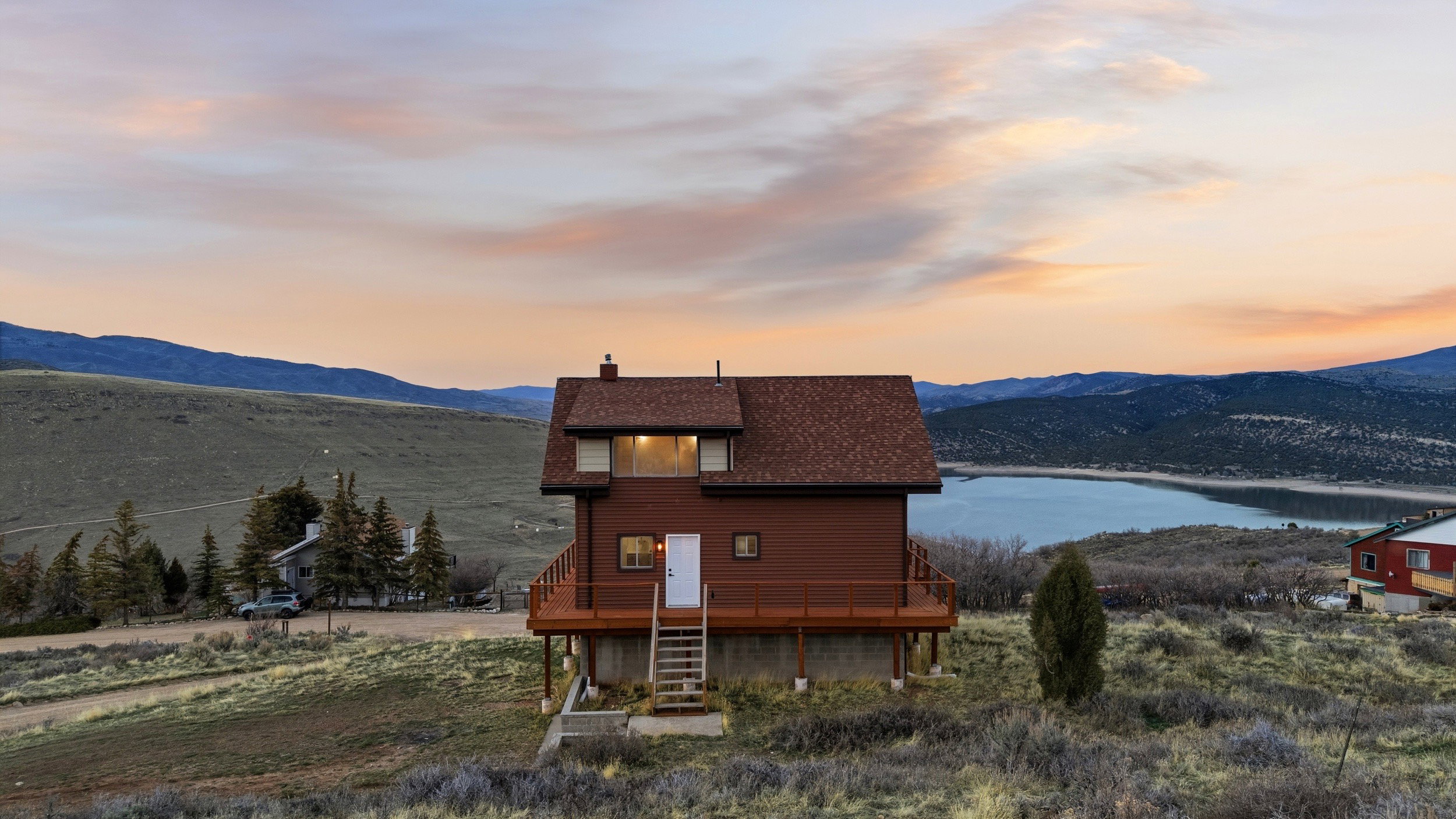 View of front of home featuring a chimney, a deck with water view, and a shingled roof