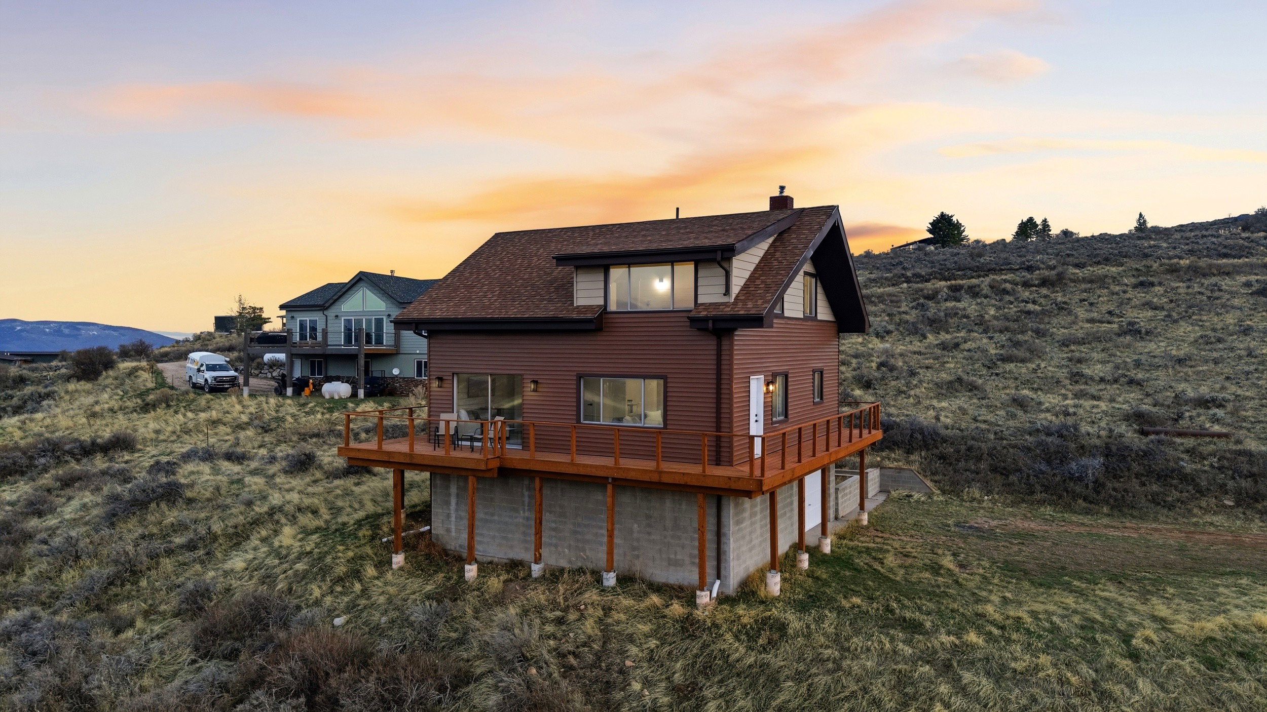 Back of house at dusk featuring a chimney and a deck with mountain view