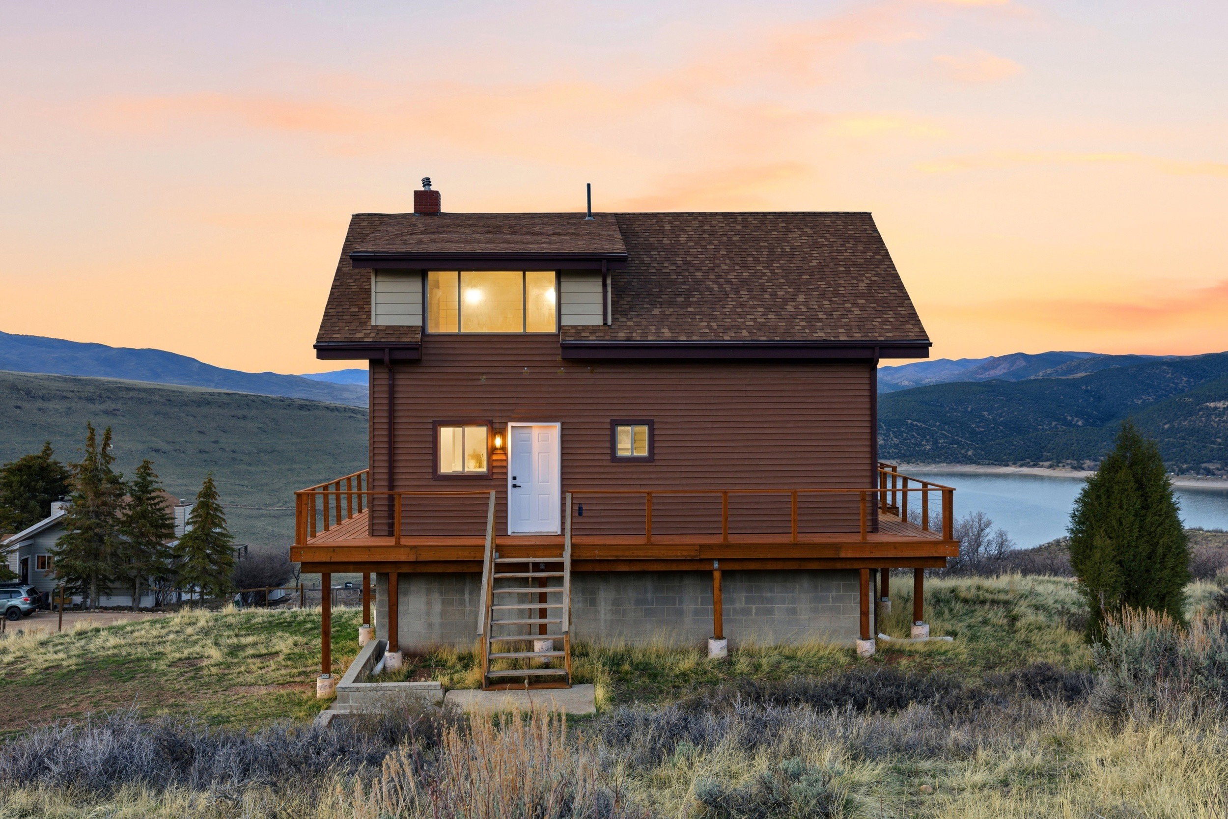Back of property at dusk with a deck with mountain view, a chimney, and a shingled roof