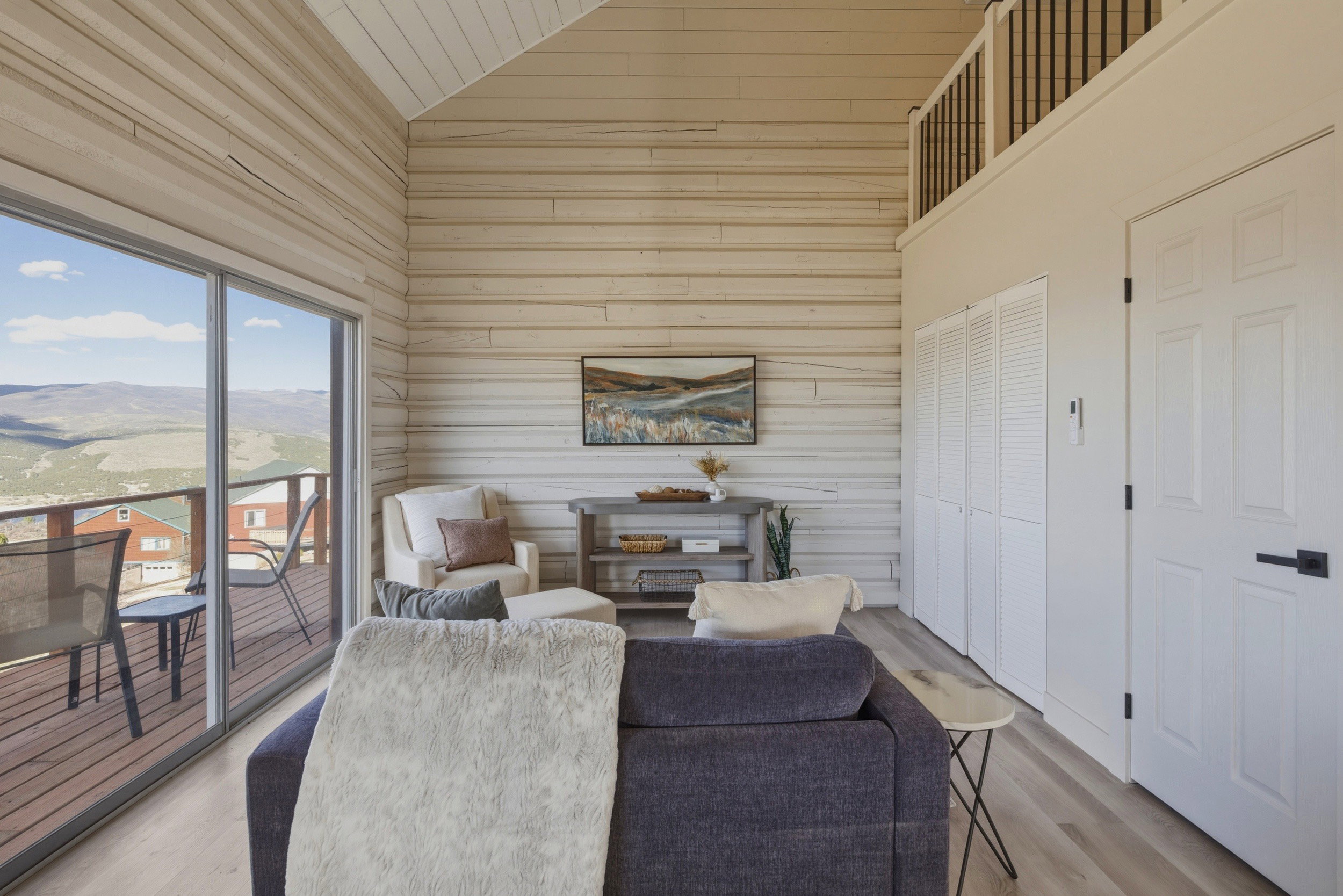 Living room featuring a mountain view, wooden walls, light wood-style floors, and a vaulted wooden ceiling