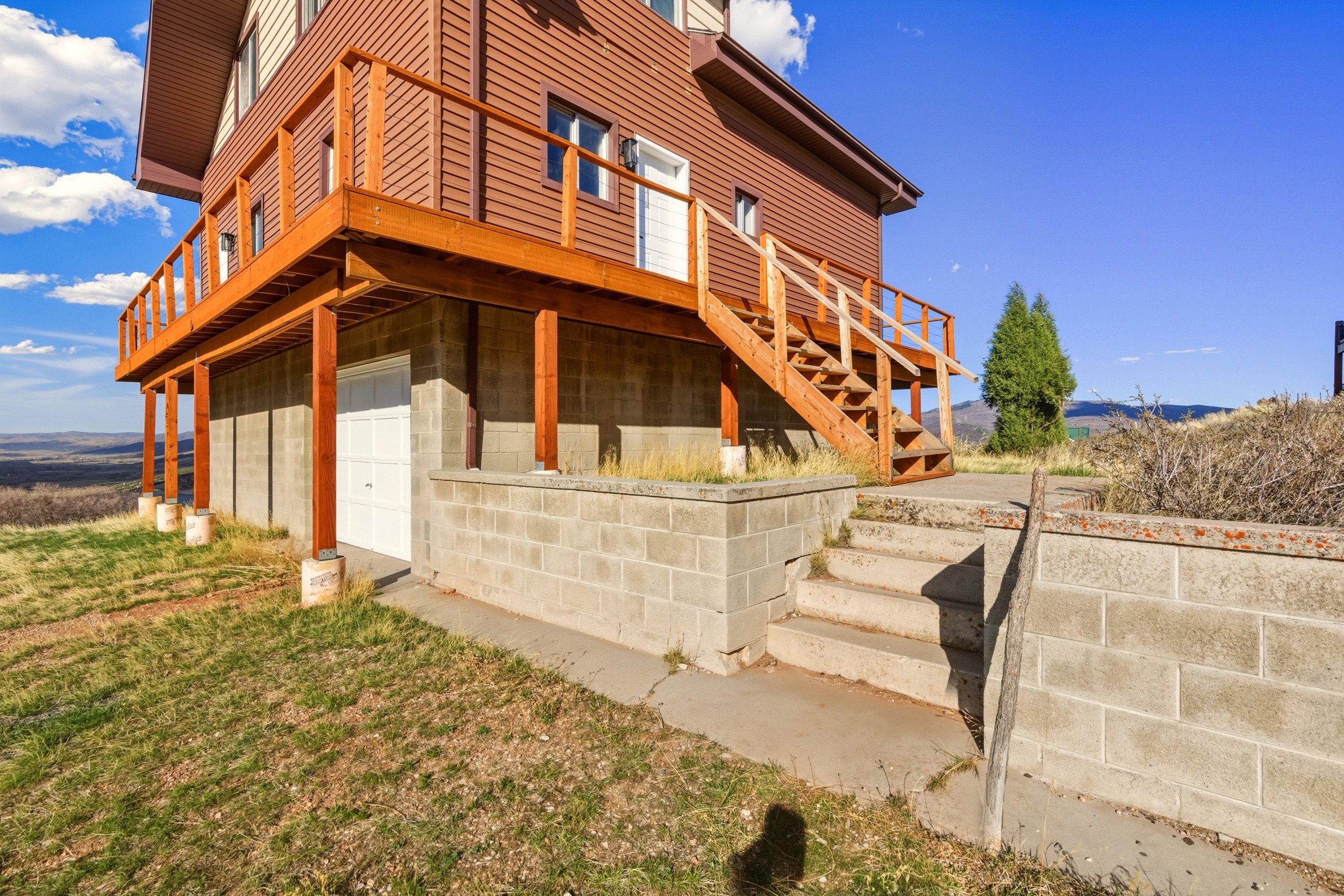 Rear view of property with stairs and an attached garage