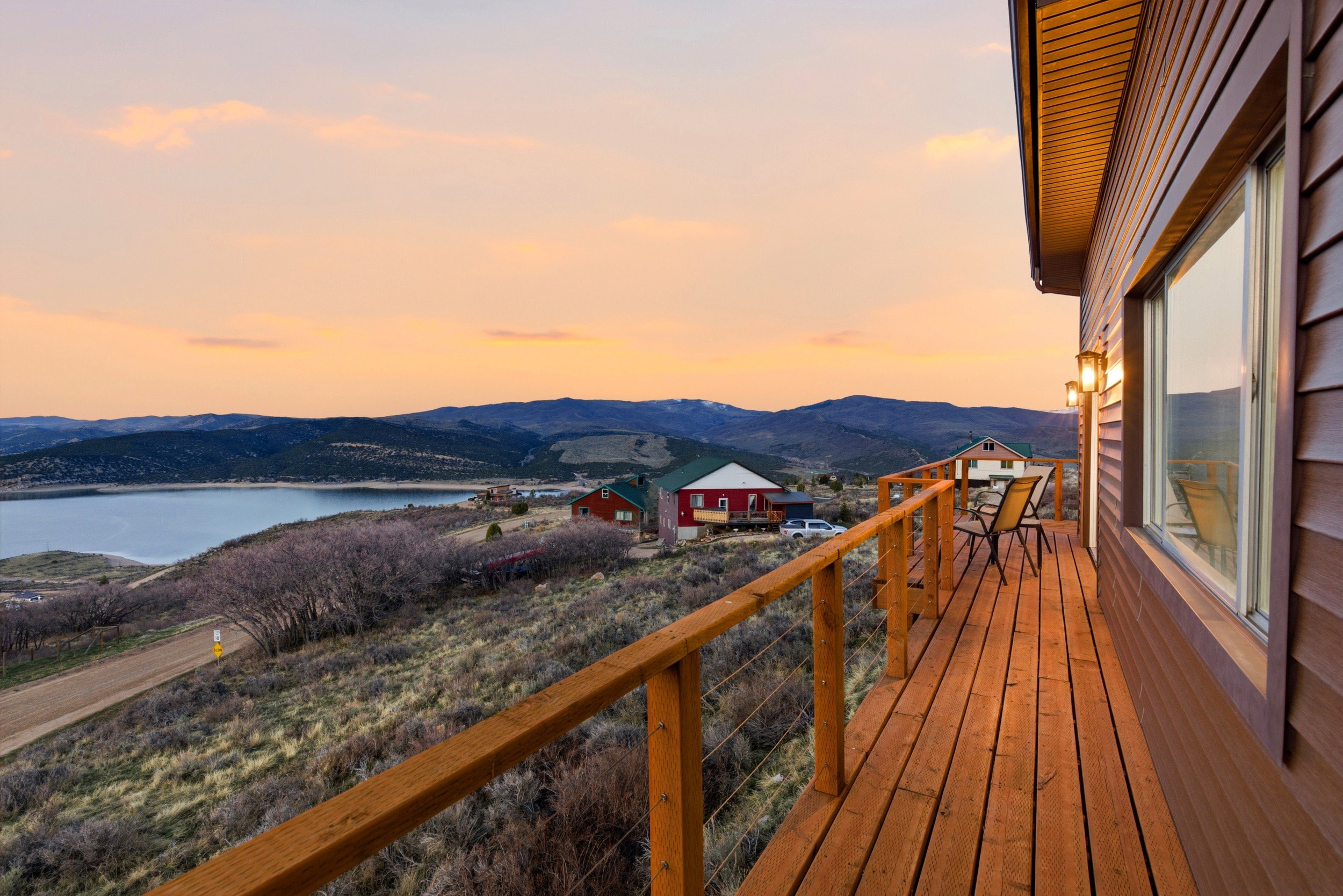 Deck at dusk with a balcony and a water and mountain view
