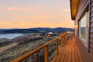 Deck at dusk with a balcony and a water and mountain view