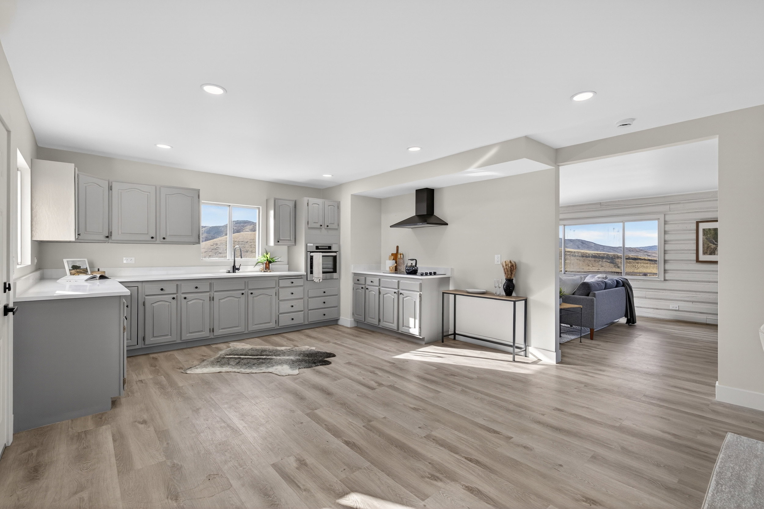 Kitchen with gray cabinets, light countertops, stainless steel oven, light wood-style floors, and recessed lighting