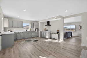 Kitchen with gray cabinets, light countertops, stainless steel oven, light wood-style floors, and recessed lighting