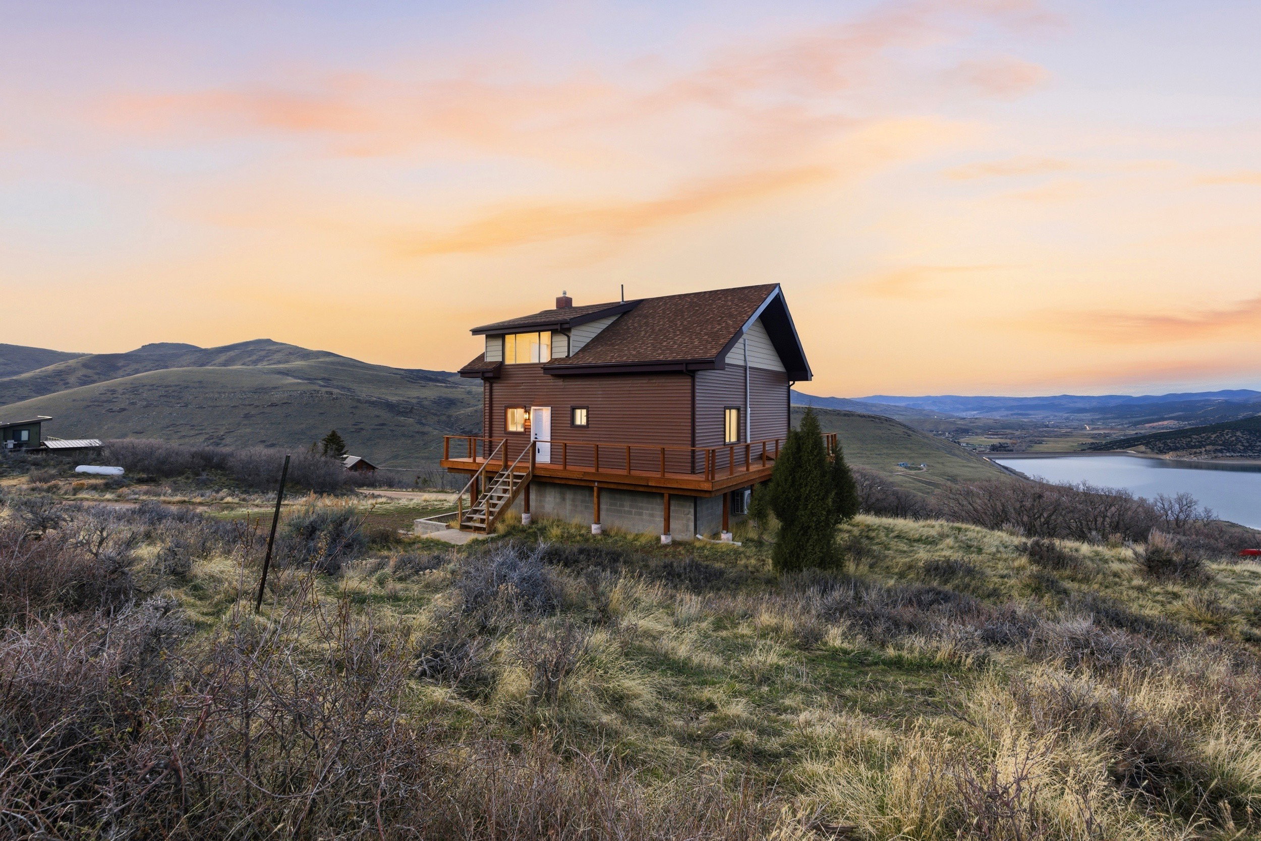 Back of house at dusk featuring a deck with water view and a chimney