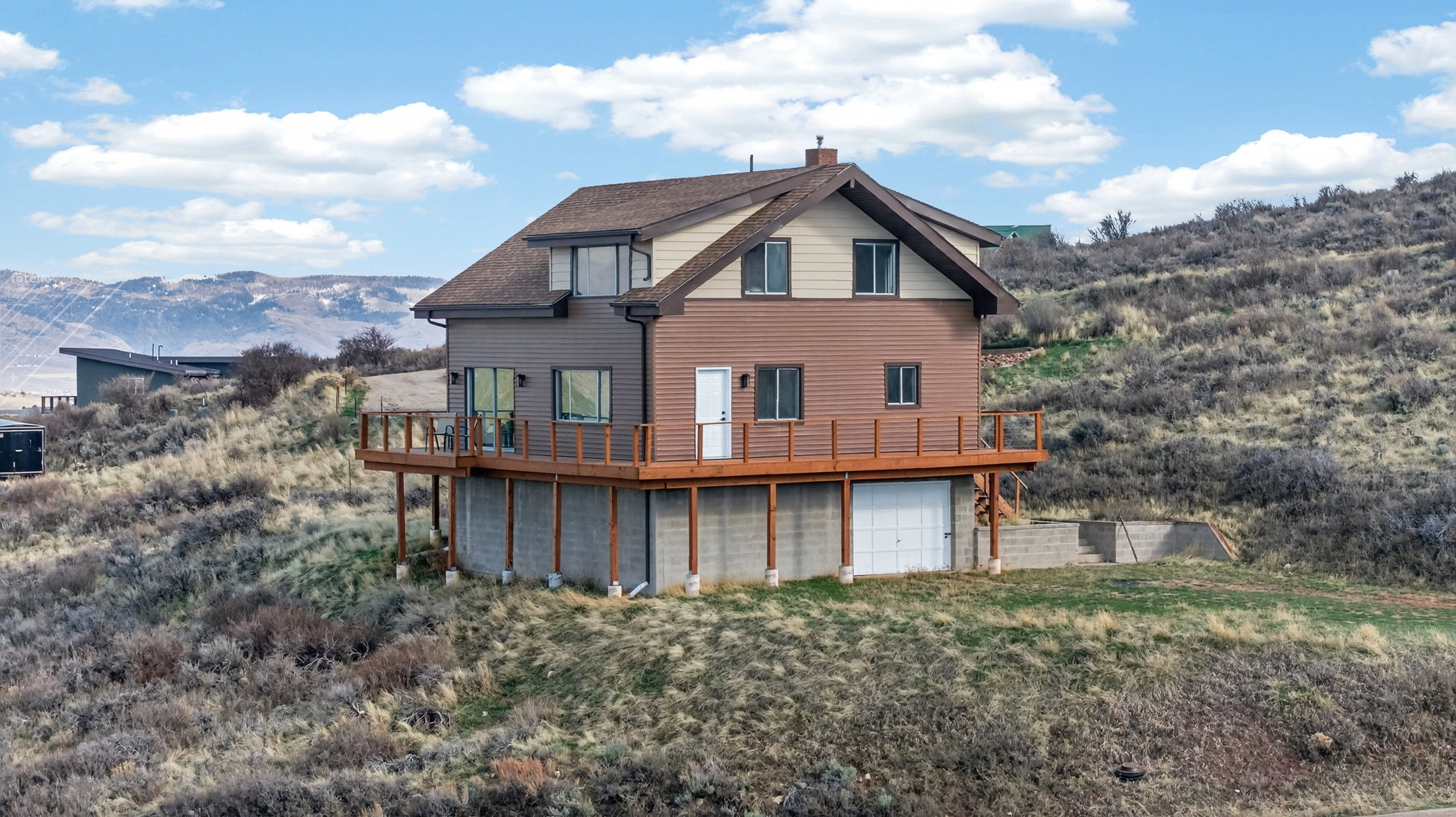 Rear view of property featuring a garage, a chimney, and a deck with mountain view