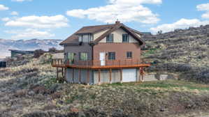 Rear view of property featuring a garage, a chimney, and a deck with mountain view