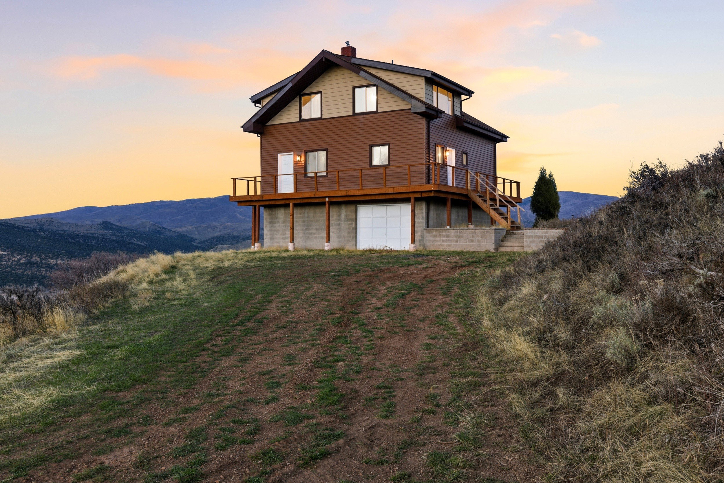 Back of property at dusk featuring a chimney, a garage, and a deck with mountain view