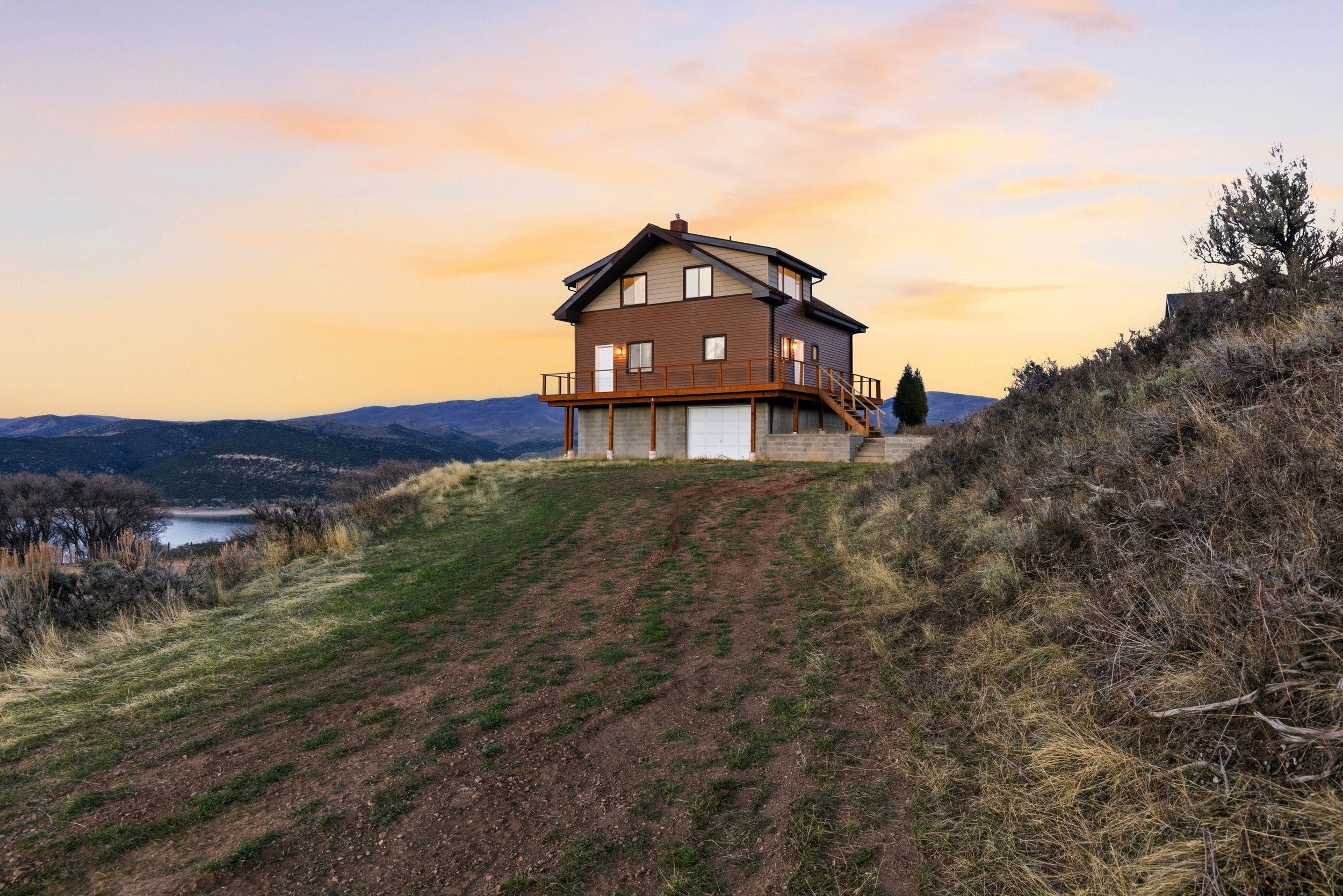 Rear view of house featuring a garage, a chimney, and a deck with water view