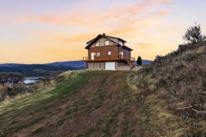 Rear view of house featuring a garage, a chimney, and a deck with water view