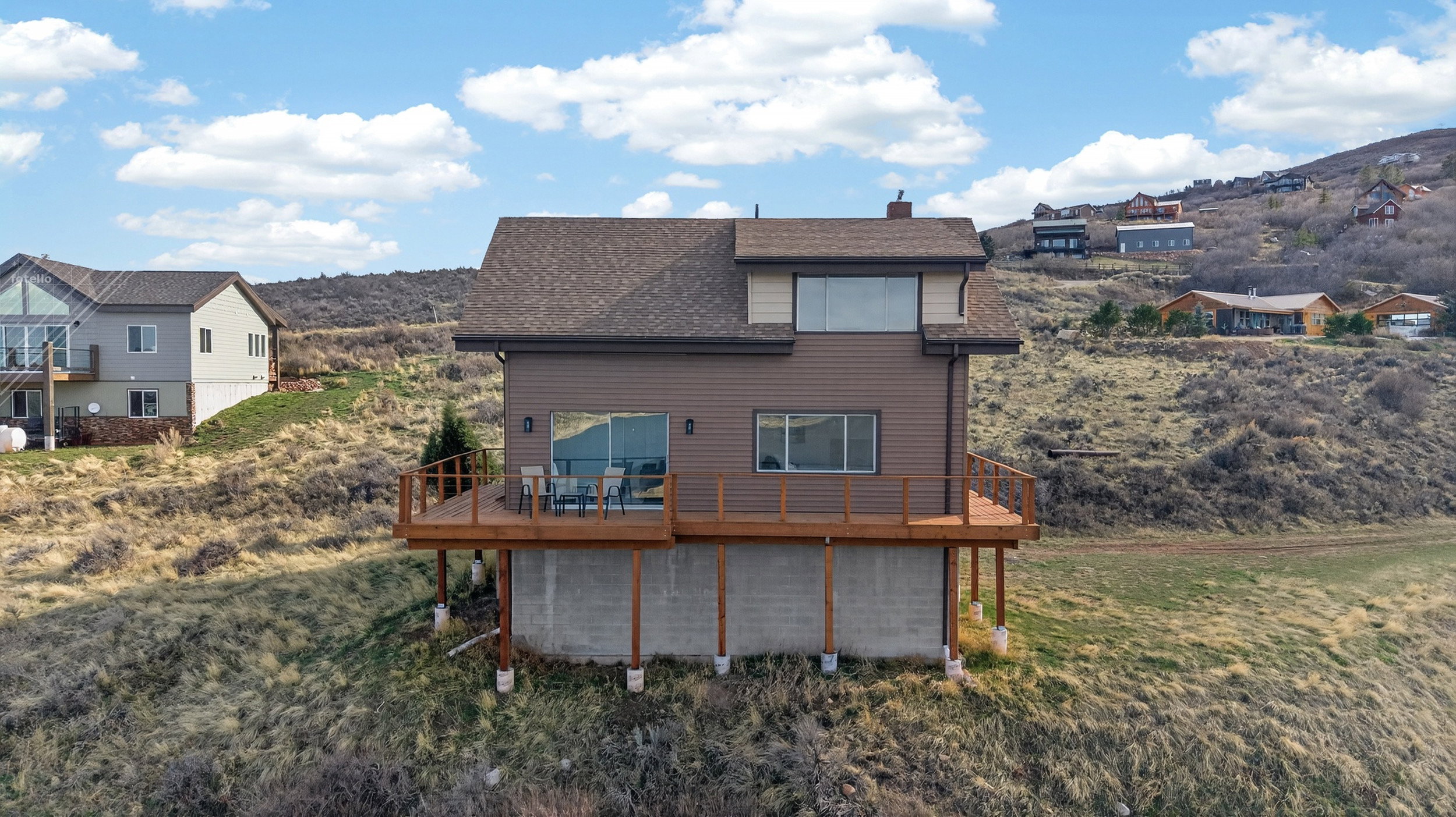 Back of property with a deck with mountain view, roof with shingles, and a chimney