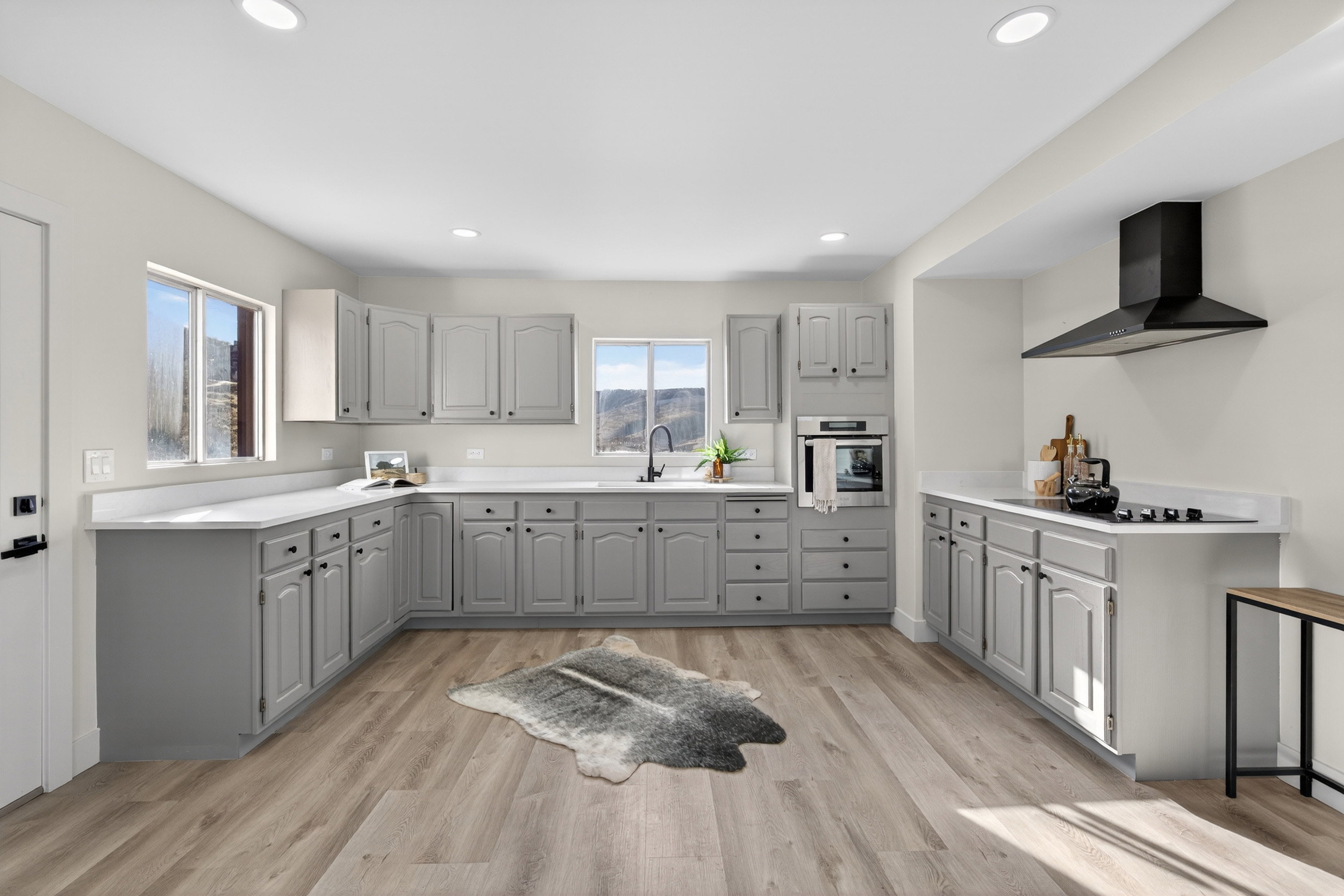 Kitchen featuring gray cabinets, light countertops, stainless steel oven, light wood-style floors, and recessed lighting