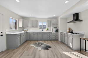 Kitchen featuring gray cabinets, light countertops, stainless steel oven, light wood-style floors, and recessed lighting