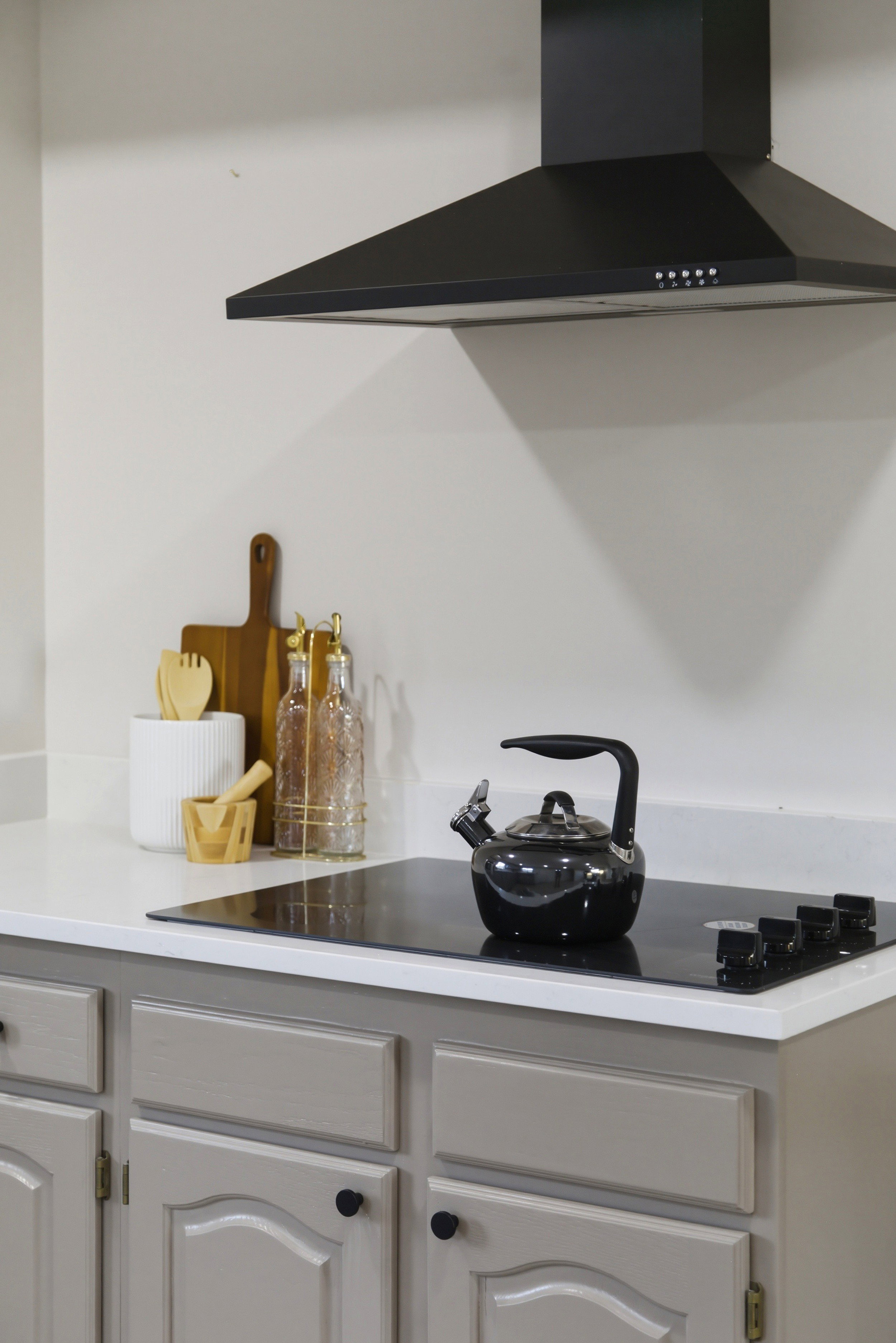 Detailed view of wall chimney range hood and black electric stovetop