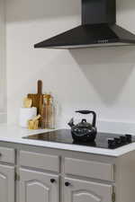 Detailed view of wall chimney range hood and black electric stovetop