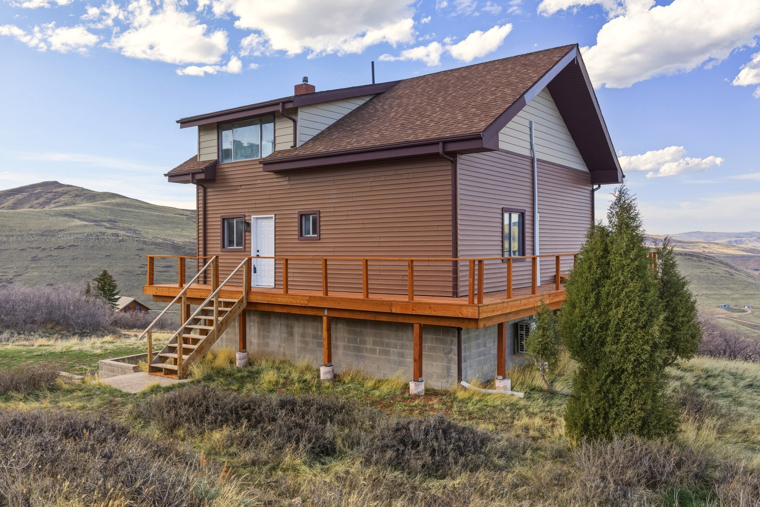 Back of house featuring a deck with mountain view, a chimney, and roof with shingles